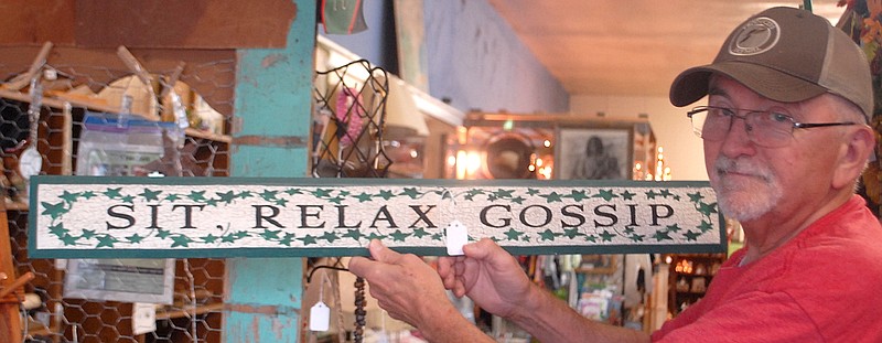 Rick Underwood of Antiques Flea Market in downtown Atlanta, Texas, holds up fun sign he's discovered.