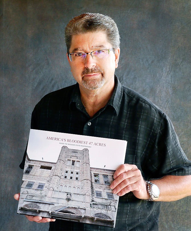 Michael Schlueter poses with his new book of Missouri State Penitentiary photographs.