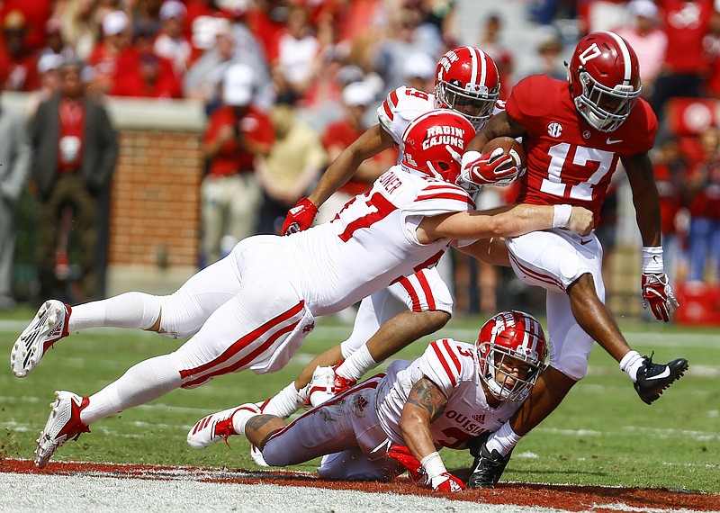 Alabama wide receiver Jaylen Waddle (17) tries to break free from the tackle of Louisiana-Lafayette defensive end Joe Dillon (3) and long snapper Jackson Ladner (57) on a punt return during the first half of an NCAA college football game, Saturday, Sept. 29, 2018, in Tuscaloosa, Ala. (AP Photo/Butch Dill)