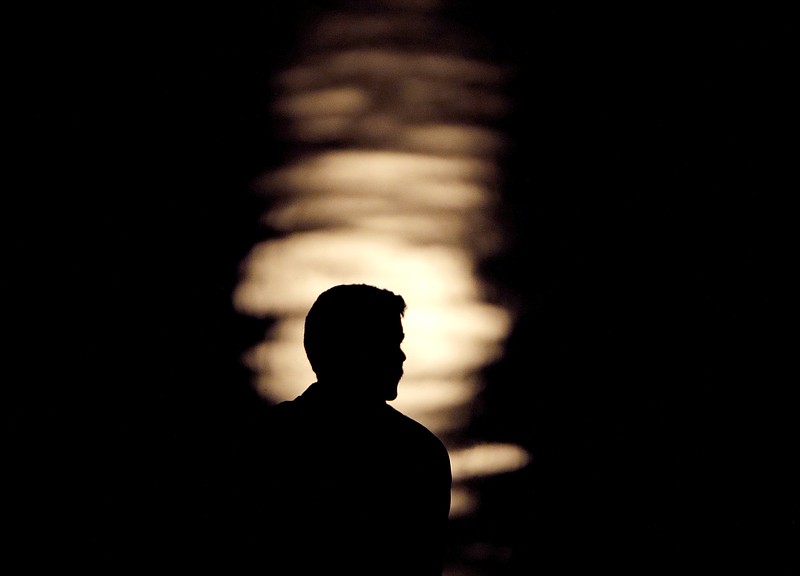 FILE- In this June 27, 2018, file photo a man is silhouetted against moonlight reflecting off the Missouri River as he watches the full moon rise beyond downtown buildings in Kansas City, Mo. A by the Associated Press-NORC Center for Public Affairs Research and MTV found that half of 15 to 26-year olds think they will eventually be better off than their parents in terms of household finances. About 29 percent expect to do as well as their parents and 20 percent expect to be worse off. (AP Photo/Charlie Riedel, File)