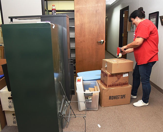 Diane Clingman tapes boxes closed as she prepares to relocate her office to the main location of the Missouri River Regional Library. Employees who currently work in the MRRL annex will have to move across the street while work is done to repair the roof and remove mold in the building.