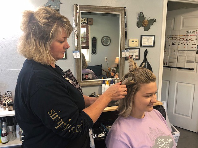 Robin Arnold curls Becca Hamilton's hair at A Good Hair Day, Clarksburg. She said turning down the heat on a flat iron can help prevent breakage from heat damage.