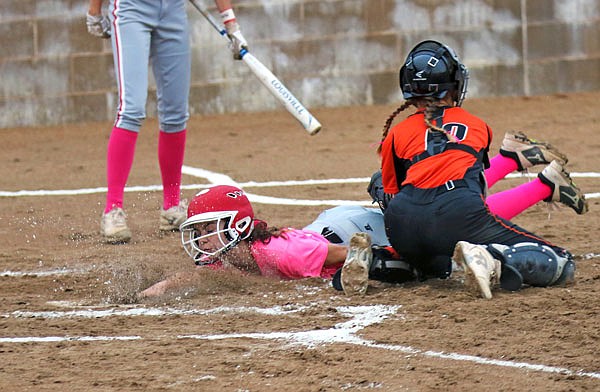 Lily McCarty of Calvary Lutheran slides past New Bloomfield catcher Kamryn Herron to score during the second inning of Thursday's game at Calvary.