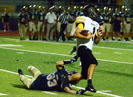 Austin Radmacher of Helias gets a grip on Monroe City's Zach Osborn during Friday night's game at Ray Hentges Stadium. 