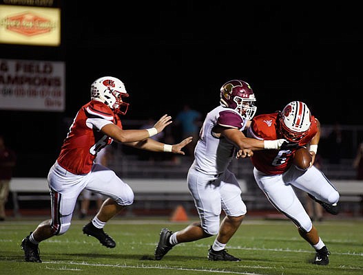 Jefferson City quarterback Devin Roberson tries to break a tackle attempt from a De Smet player while Ian Cote looks to help during Friday night's game at Adkins Stadium.