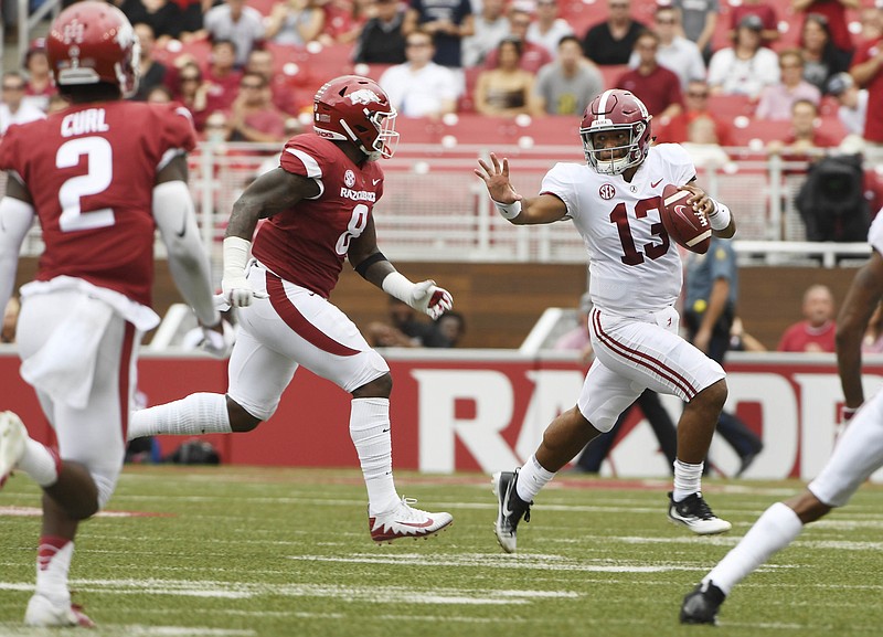 Alabama quarterback Tua Tagovailoa (13) tries to get away from Arkansas defender De'Jon Harris in the first half of an NCAA college football game Saturday, Oct. 6, 2018, in Fayetteville, Ark. (AP Photo/Michael Woods)
