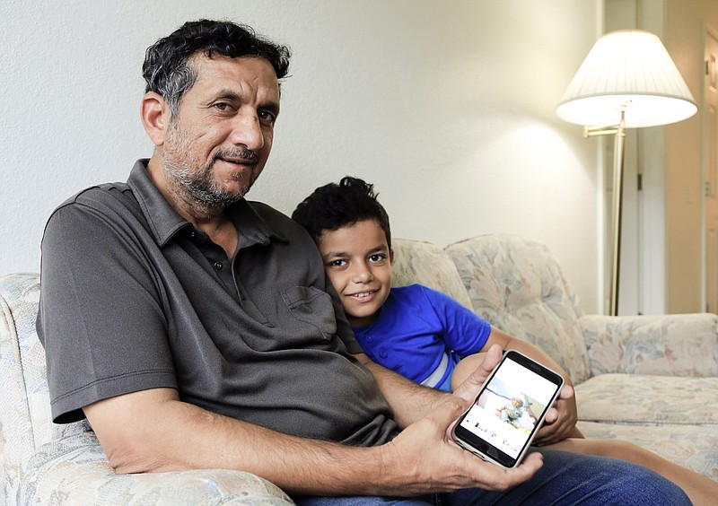 Hadi Mohammed sits with his 9-year-old son Mohammed Ghaleb on Sept. 29 in their Lincoln, Neb. apartment. Death threats drove Hadi Mohammed out of Iraq and to a small apartment in Nebraska, where he and his two young sons managed to settle as refugees. But the danger hasn't been enough to allow his wife to join them. 