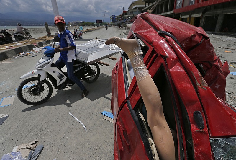 A mannequin leg sticks out from a heavily damaged car at a tsunami-ravaged area in Palu, Central Sulawesi, Indonesia, Tuesday, Oct. 9, 2018. A 7.5 magnitude earthquake rocked Central Sulawesi province on Sept. 28, triggering a tsunami and mudslides that killed a large number of people and displaced tens of thousands of others. (AP Photo/Dita Alangkara)