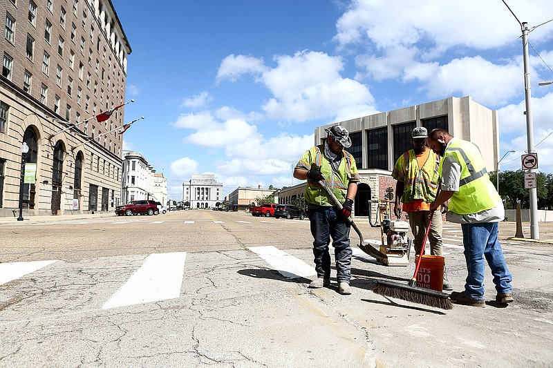 Ian Harvey, Jamon Smith and James Hines from Total Highway Maintenance work on removing the stop bar Monday on North State Line Avenue and Third Street in Texarkana.