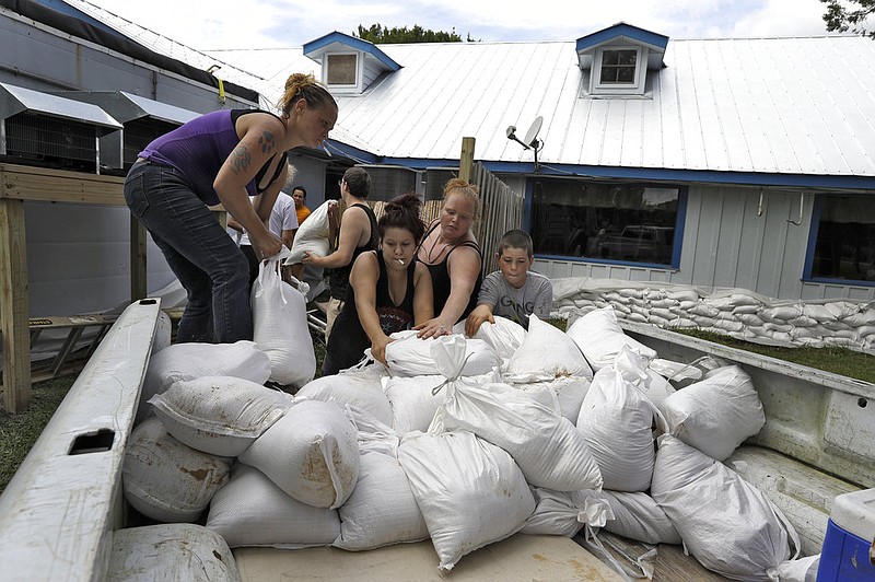 Krystal Day, of Homosassa, Fla., left, leads a sandbag assembly line at the Old Port Cove restaurant Tuesday, Oct. 9, 2018, in Ozello, Fla. Employees were hoping to protect the restaurant from floodwaters as Hurricane Michael continues to churn in the Gulf of Mexico heading for the Florida panhandle. (AP Photo/Chris O'Meara)