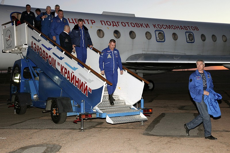 In this photo provided by Roscosmos, Russian cosmonaut Alexey Ovchinin, center, and U.S. astronaut Nick Hague, center left, arrive in Baikonur airport, Kazakhstan, Thursday, Oct. 11, 2018, after an emergency landing following the failure of a Russian booster rocket carrying them to the International Space Station. (Roscosmos via AP)