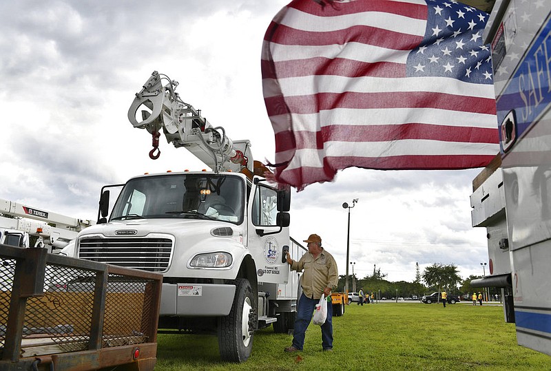 An employee of Southern Electric Corporation from Flowood, Miss., climbs out of the cab of his truck after arriving at the Sarasota Fairgrounds Tuesday, Oct. 9, 2018. Florida Power & Light is staging their power restoration contractors in Sarasota, Fla., in advance of Hurricane Michael's expected landfall in the Florida panhandle later this week. (Mike Lang/Sarasota Herald-Tribune via AP)