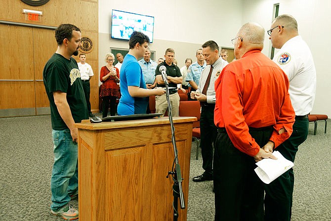 Joseph Gray (left) watches while his son, Langdon, was honored at Fulton's City Council meeting this week. State Fire Marshal Tim Bean presented him with a certificate, three Challenge coins and a uniform patch, and he also was recognized by Fulton Fire Chief Kevin Coffelt and Mayor LeRoy Benton. The family's home burned down in August, but Langdon, 13, awoke members of his family including two younger children, all of whom made it to safety.