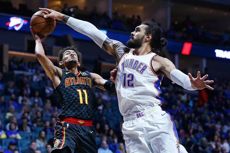 In this Oct. 7, 2018, file photo, Oklahoma City Thunder center Steven Adams (12) blocks a shot by Atlanta Hawks guard Trae Young (11) in the first half of an NBA preseason basketball game in Tulsa, Okla. The narrative on the demise of the big man in the NBA may have been a bit premature. At the very least it has been misinterpreted. Their roles have been defined, but Steven Adams, DeMarcus Cousins, Anthony Davis, Nikola Jokic, Clint Capela and others have shown teams still covet a dominant center. (AP Photo/Sue Ogrocki, File)