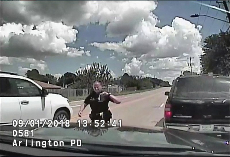 In this screenshot taken from Sept. 1, 2018, police dashboard camera video provided by the Arlington Police Department, an officer walks back to her cruiser after stopping O'Shae Terry for a vehicle registration violation in Arlington, Texas. Moments later, a backup officer who's standing at the passenger-side door of Terry's vehicle, fires shots into the SUV after its window rolled up and the vehicle started moving forward. Terry was killed. (Arlington Police Department via AP)