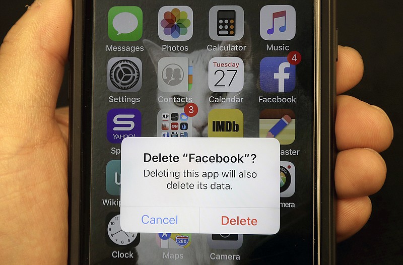 FILE - In this March 27, 2018, file photo, a reporter holds a phone showing the Facebook app in San Francisco. It might not seem like a big deal to have  long-forgotten accounts on social media linger. But with hacking in the news constantly, including a breach affecting 50 million Facebook accounts, you might not want all that data sitting around. (AP Photo/Jeff Chiu, File)