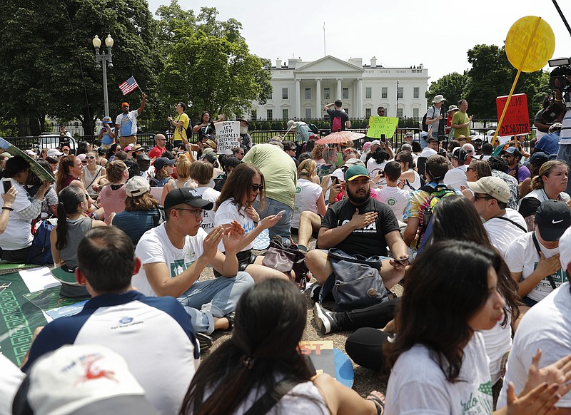FILE - In this April 29, 2017, file photo, demonstrators sit on the ground along Pennsylvania Ave. in front of the White House in Washington. The National Park Service is exploring the question of whether it should recoup from protest organizers the cost of providing law enforcement and other support services for demonstrations held in the nation's capital. The proposed rule also could place new limits on spontaneous demonstrations and shrink a significant portion of the White House sidewalk accessible to the public. (AP Photo/Pablo Martinez Monsivais, File)