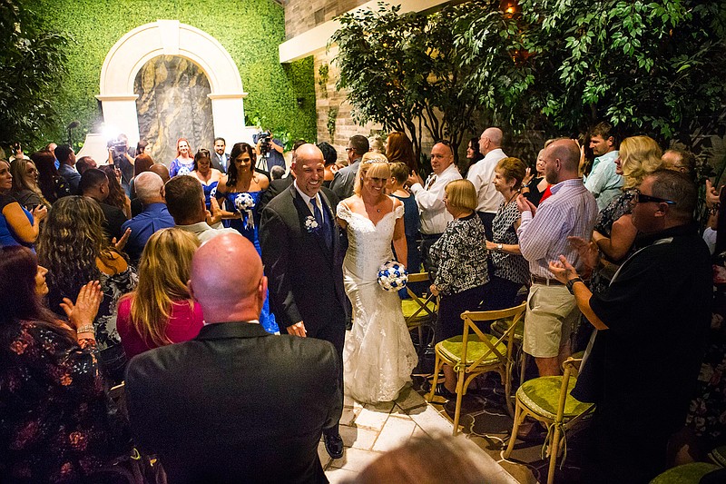 In this Oct. 1, 2018 photo, Todd Wienke and Oshia Collins-Waters walk down the aisle at the conclusion of their wedding ceremony at Chapel of the Flowers in Las Vegas. Todd was shot three times as he shielded Oshia soon after the shooting began the night of Oct. 1, 2017. (Chase Stevens/Las Vegas Review-Journal via AP)