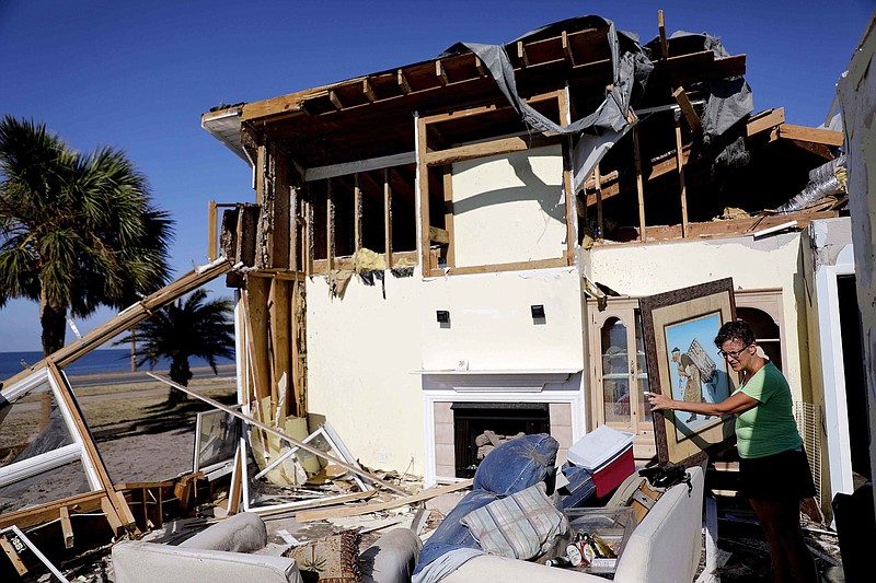 Marla Wood pulls a framed art piece out of the rubble of her damaged home from Hurricane Michael in Mexico Beach, Fla., Sunday, Oct. 14, 2018. (AP Photo/David Goldman)