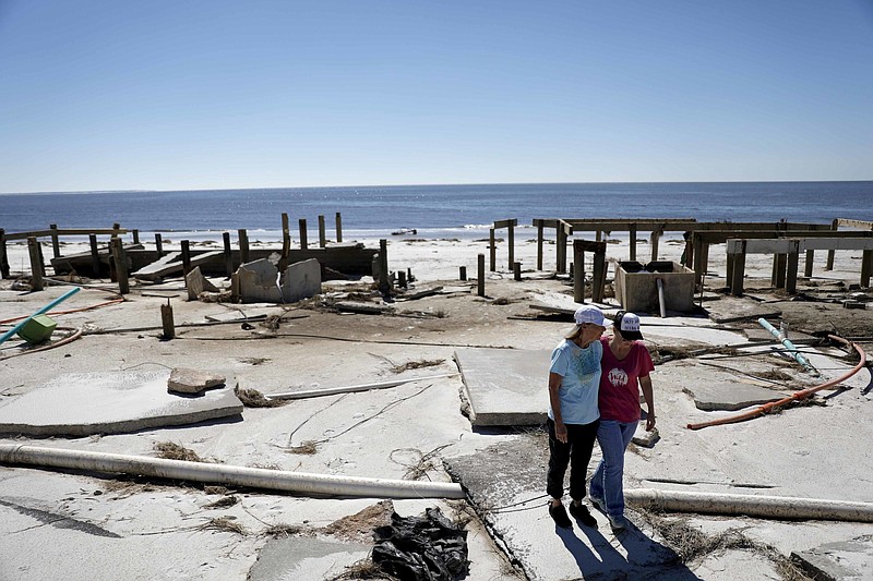 FILE - In this Oct. 12, 2018, file photo, Joy Hutchinson, left, is comforted by her daughter Jessica Hutchinson, as she returns to find her home swept away from hurricane Michael in Mexico Beach, Fla. It was once argued that the trees would help save Florida’s Panhandle from the fury of a hurricane, as the acres of forests in the region would provide a natural barrier to savage winds that accompany the deadly storms. It’s part of the reason that tighter building codes, mandatory in places such as South Florida, were not put in place for most of this region until just 11 years ago. And it may be a painful lesson for area residents now that Hurricane Michael has ravaged the region (AP Photo/David Goldman, File)