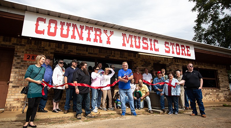 Owner Ed Strange cuts the Atlanta Chamber of Commerce ribbon Friday for the grand opening of the Country Music Store in Atlanta, Texas. The store specializes in musical instruments; its flagship guitar line is from C.F. Martin & Co. Strange moved the business from Texarkana to Atlanta to be closer to home. The store is at 2814 W. Main St.