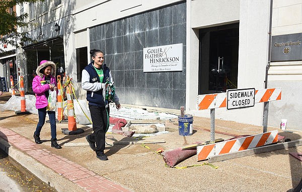 Allysia, front, and Olivia Waldrop walk past sidewalk repairs Monday, Oct. 15, 2018, in downtown Jefferson City at 131 E. High St. 