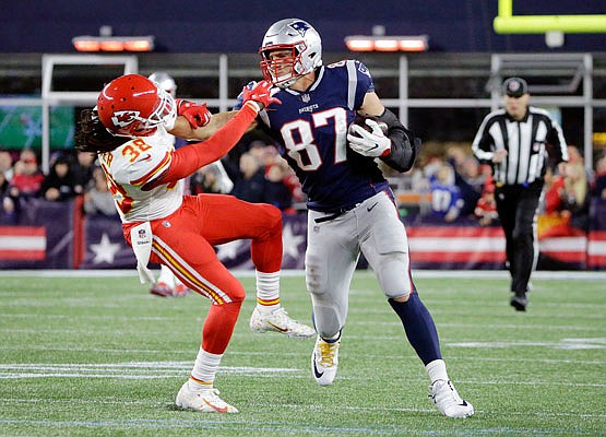 Patriots tight end Rob Gronkowski gives a stiff arm to Chiefs free safety Ron Parker after catching a pass late in Sunday night's game in Foxborough, Mass.