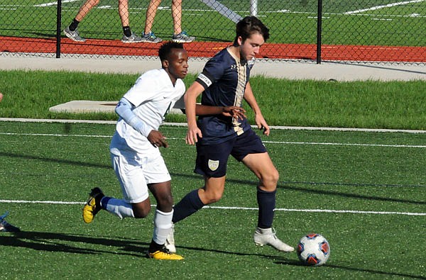 Carson Mudd of the Helias Crusaders drives past a Kansas City East defender toward the net during Monday's game at the Crusader Athletic Complex.