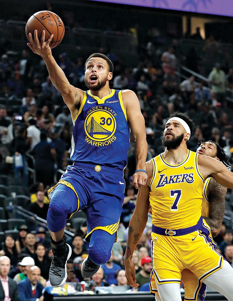  Golden State Warriors guard Stephen Curry shoots next to Los Angeles Lakers center JaVale McGee during a preseason game Friday in Las Vegas. The Warriors start their title defense tonight against Oklahoma City.
