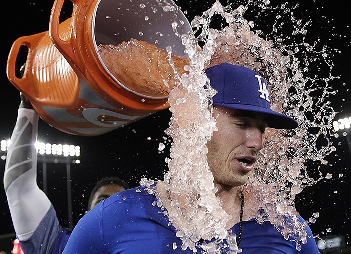 Los Angeles Dodgers' Cody Bellinger is dunked by Yasiel Puig after hitting a walk-off hit during the 13th inning of Game 4 of the National League Championship Series baseball game against the Milwaukee Brewers Tuesday, Oct. 16, 2018, in Los Angeles. The Dodgers won 2-1 to tie the series at 2-2. (AP Photo/Jae Hong)