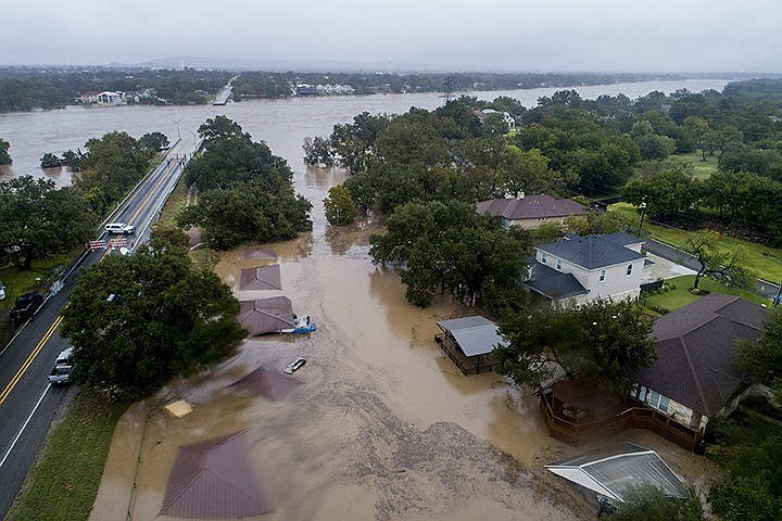 The Llano River overflows its banks into neighboring property as the swollen river flows between the washed out Ranch Road 2900 bridge, background, Tuesday, Oct. 16, 2018, in Kingsland, Texas. (Jay Janner/Austin American-Statesman via AP)