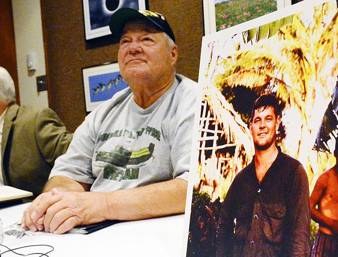 Roger Thompson, who served during the Vietnam War as a member of the United States Navy, poses with a photo of himself in Vietnam from 1968 as he waits to speak during a seminar Thursday at the Missouri River Regional Library. The event, "Strength and Honor: Reflections from Veterans of the Vietnam War," was co-hosted by Operation Bugle Boy.