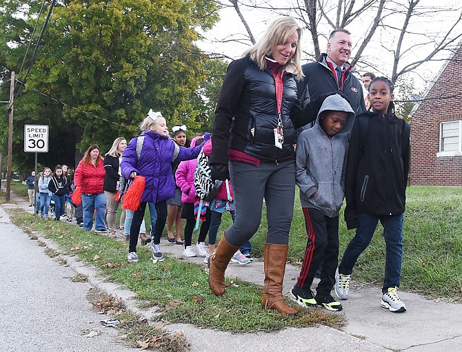 Students Maurice Crudup, left, and Da'Caveon Nelson walk with East Elementary School counselor Ruthie Eichholz and Jefferson City Public Schools Superintendent Larry Linthacum and a couple of dozen students and school staff Thursday, Oct. 18, 2018, on Riverside Drive to East School. They participated in the 2018 Walk to School Day which is designed to improve youth health by encouraging those students who live in close proximity to walk to school. 