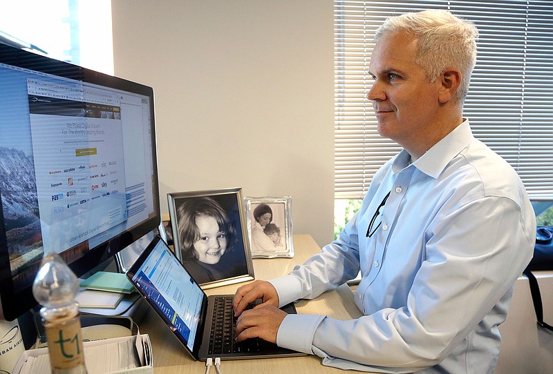 In this Tuesday, Oct. 2, 2018, photo Urban Airship product and engineering executive Mike Herrick works at his desk with photos of his daughter, Lauren, and wife Erin at his side in Portland, Ore. The tensions between the pride Herrick takes in his profession and his parental qualms about technology tug particularly hard when he sees his daughter, Lauren, and her friends texting each other instead of talking when they're sitting 5 feet apart. (AP Photo/Don Ryan)