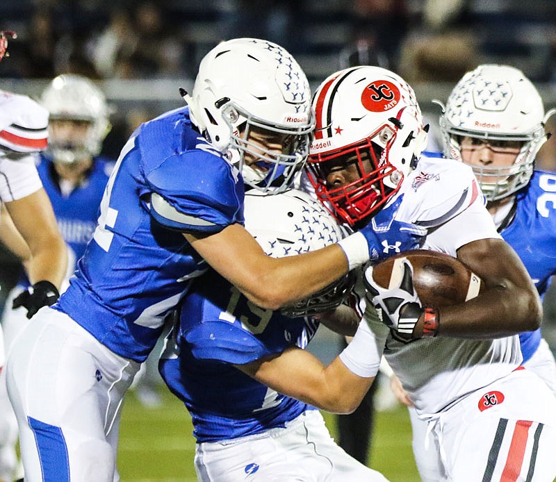 Jefferson City running back Maleek Jackson gets wrapped up by Rockhurst teammates Carter Elder (19) and Mitch Tarwater during Friday night's game in Kansas City.