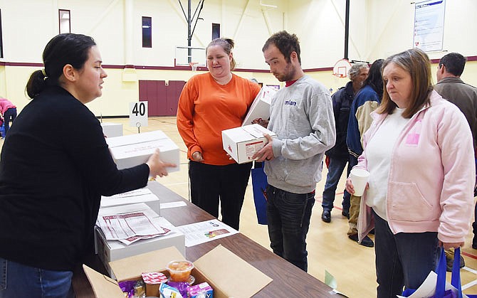 2018 FILE: Michelle Kelsey, right, along with her son Jared Maute and daughter-in-law Dannielle Maute, accept prepackaged food boxes in October 2018 from Cristal Backer as they visited booths in the First Christian Church gymnasium. Backer is the regional coordinator of The Food Bank for Central and Northeast Missouri, one of the participants in Friday's fourth annual Project Homeless Connect. A number of Jefferson City churches along with employment and social services agencies, veterans' support groups and health services combined to offer services for area people facing homelessness.