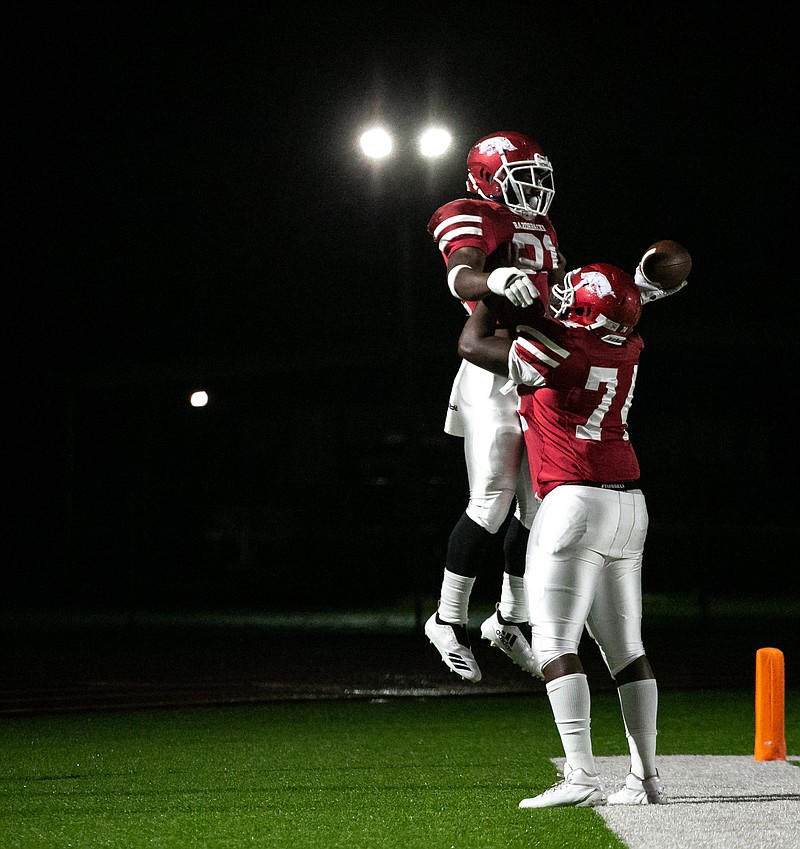 Razorbacks' running back Cameron Collier is picked up by a teammate after scoring the first touchdown from the first kickoff from the Hot Springs Trojans on Friday at Arkansas High School in Texarkana, Ark.