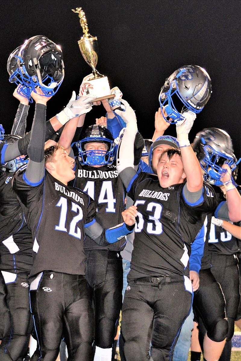 From left, South Callaway junior running back Devin Borghardt (12), senior wide receiver Dylan Paschang (14) and senior lineman Dustin Loucks (53) celebrate with their teammates after the Bulldogs held off the North Callaway Thunderbirds 33-32 in overtime in the annual Callaway Cup rivalry game Friday night in Mokane.
