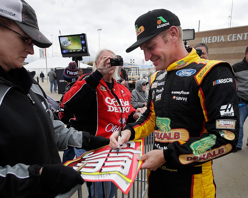 NASCAR Cup Series driver Clint Bowyer, right, gives autographs after practicing for the weekend's auto race at Kansas Speedway in Kansas City, Kan., Friday, Oct. 19, 2018. (AP Photo/Orlin Wagner)