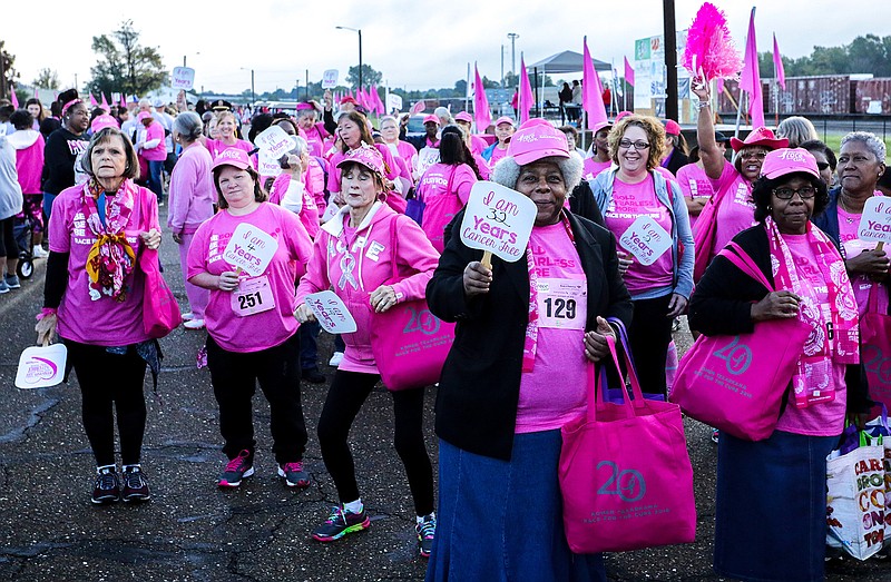 Breast cancer survivors march in pink holding fans stating how many years they have been cancer free Saturday on Front Street in downtown Texarkana, Ark., before the Race for the Cure 5K event. The annual event lets survivors celebrate being cancer free and promotes awareness. 