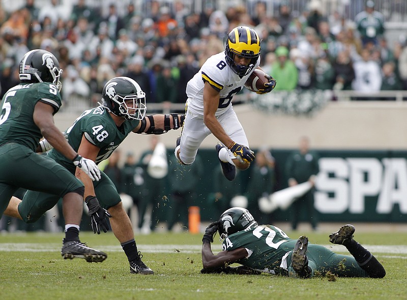 Michigan receiver Ronnie Bell (8) leaps over Michigan State's Tre Person (24) as Michigan State's Andrew Dowell (5) and Kenny Willekes (48) pursue during the second quarter of an NCAA college football game, Saturday, Oct. 20, 2018, in East Lansing, Mich. (AP Photo/Al Goldis)