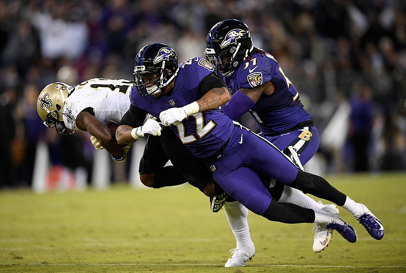 Baltimore Ravens defensive back Jimmy Smith (22) and linebacker C.J. Mosley, right, tackle New Orleans Saints wide receiver Michael Thomas, left, Sunday in Baltimore.