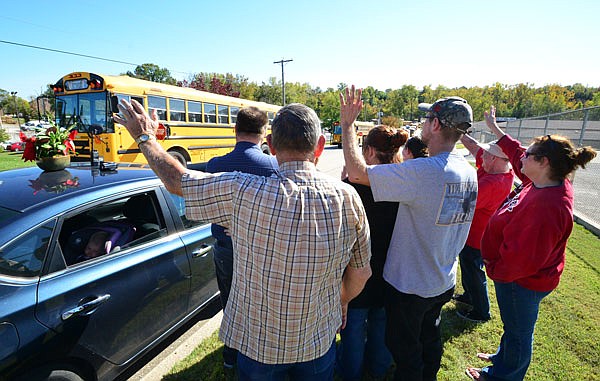 The family of John Kalina, who died over the weekend, pay tribute by gathering Monday at the corner of Industrial and Norman drives to wave at passing First Student buses driven by Kalina's co-workers. 