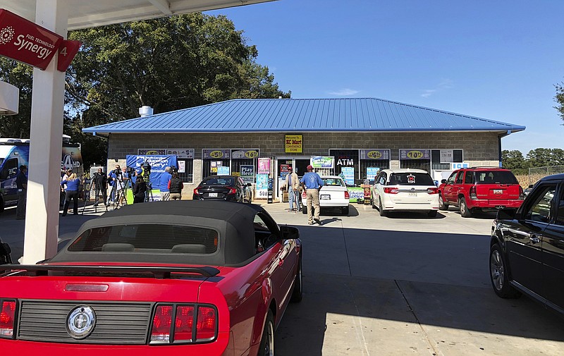 Media at left, record people entering the KC Mart in Simpsonville, S.C., on Wednesday, Oct. 24, 2018, after it was announced the winning Mega Millions lottery ticket was purchased at the store. Unless the winner chooses to come forward, the world may never know who won. (AP Photo/Jeffrey Collins)