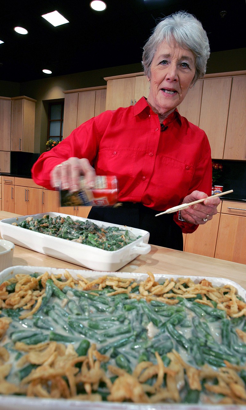 In this Nov. 15, 2005 file photo, a Green Bean Cassorole sits in the foreground as Dorcas Reilly prepares another at the Campbell Soup Co. corporate kitchen in Camden, N.J.  Reilly died on Monday, Oct. 15, 2018 and her family will celebrate her life on Saturday, Oct. 27 in the town where she lived, Haddonfield, N.J. Reilly was a Campbell Soup kitchen supervisor in 1955 when she combined green beans and cream of mushroom soup, topped with crunchy fried onions, for an Associated Press feature. It is the most popular recipe ever to come out of the corporate kitchen at Campbell Soup.  (AP Photo/Mel Evans, File)