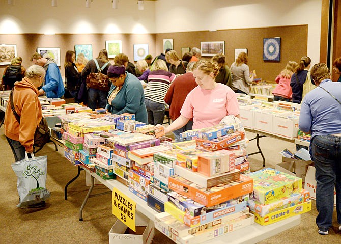 Visitors look through rows of books and board games Friday during the Pop Up Book Sale at Missouri River Regional Library. 