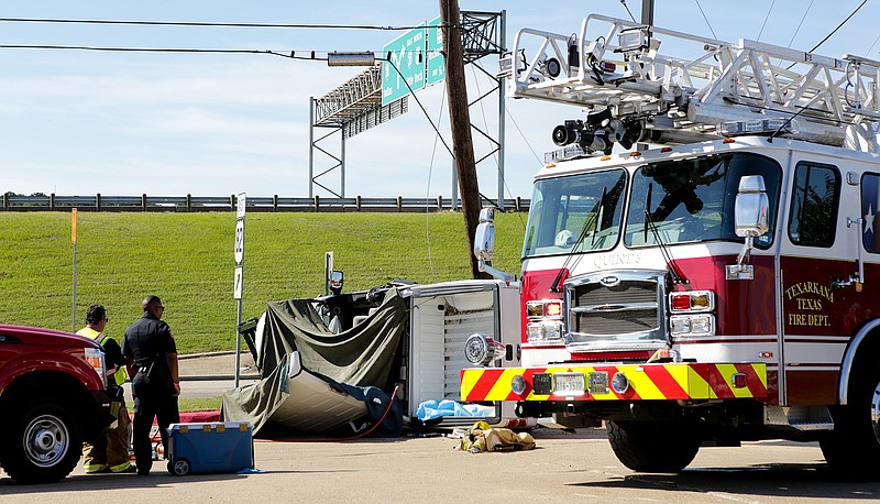 A Texarkana, Texas, firefighter and a police officer look at the overturned truck where Randy Smith, 62, of Texarkana, Ark., was pronounced dead at the scene on Monday on Piney Road near U.S. Highway 82. Smith suffered a possible medical issue that caused him to strike a utility pool. Smith's wife and four grand- children, who were also in the vehicle, were sent to the hospital with non-life threatening injures.