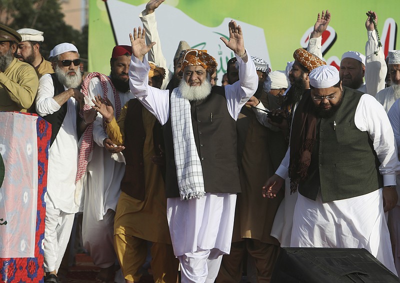 Maulana Fazaur Rehman, center, leader of the Muttahida Majlis-e-Amal Alliance waves to his supporters rally against the acquittal of Pakistani Christian woman Asia Bibi, in Karachi, Pakistan, Thursday, Nov. 8, 2018. A Christian woman acquitted after eight years on death row in Pakistan for blasphemy was released but her whereabouts in Islamabad on Thursday remained a closely guarded secret in the wake of demands by radical Islamists that she be publicly executed. (AP Photo/Fareed Khan)