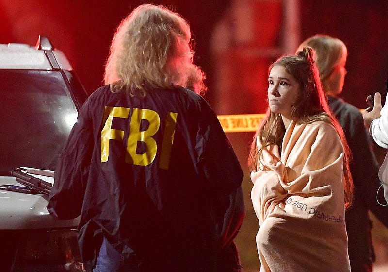 An FBI agent talks to a potential witness as they stand near the scene Thursday, Nov. 8, 2018, in Thousand Oaks, Calif. where a gunman opened fire Wednesday inside a country dance bar crowded with hundreds of people on "college night."  (AP Photo/Mark J. Terrill)

