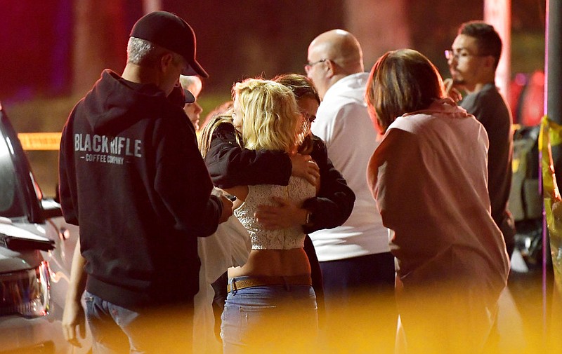 People comfort each other as they stand near the scene Thursday, Nov. 8, 2018, in Thousand Oaks, Calif., where a gunman opened fire Wednesday inside a country dance bar crowded with hundreds of people on "college night," killing multiple people including a deputy who rushed to the scene.